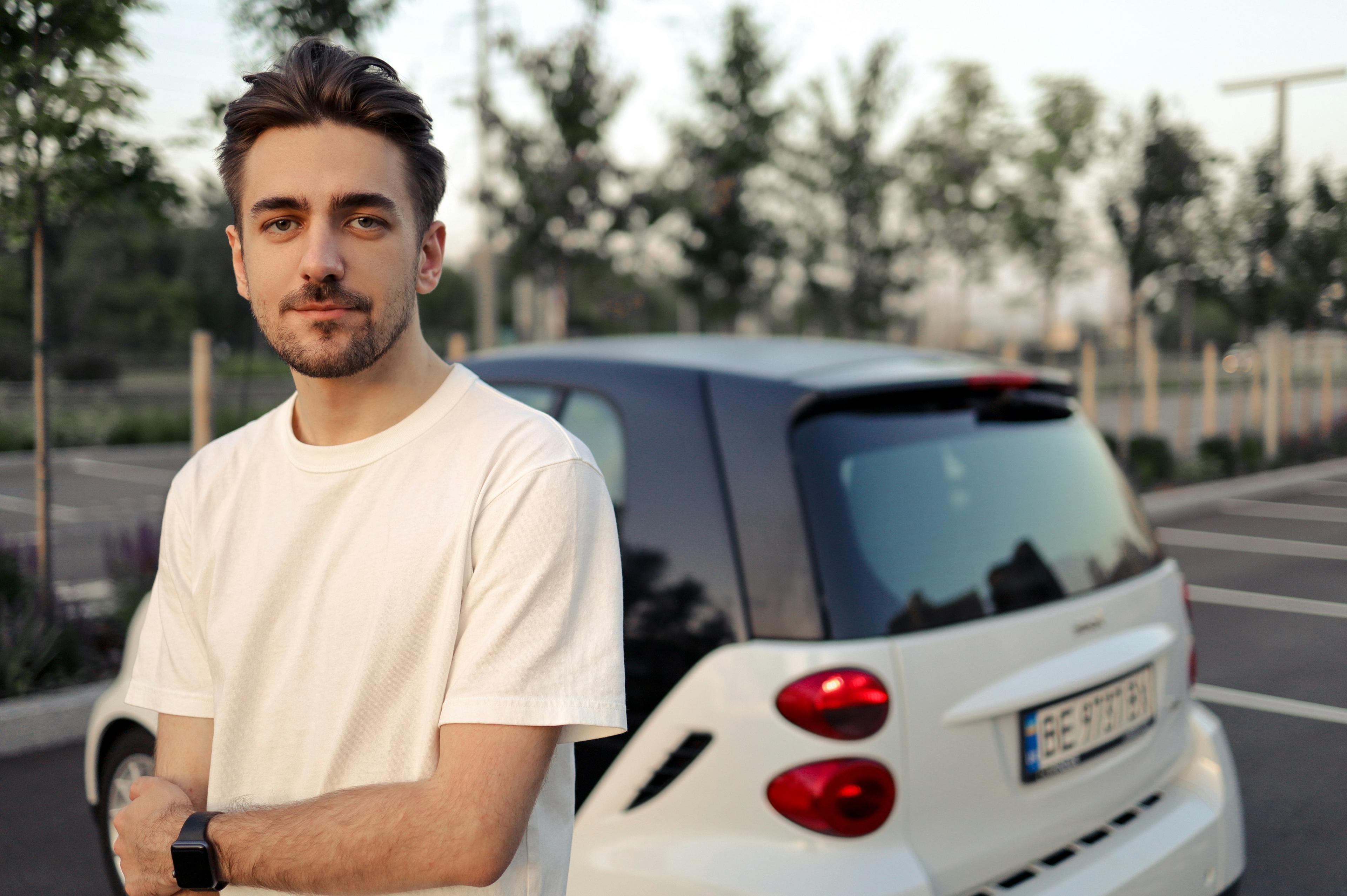 A student standing in front of a car