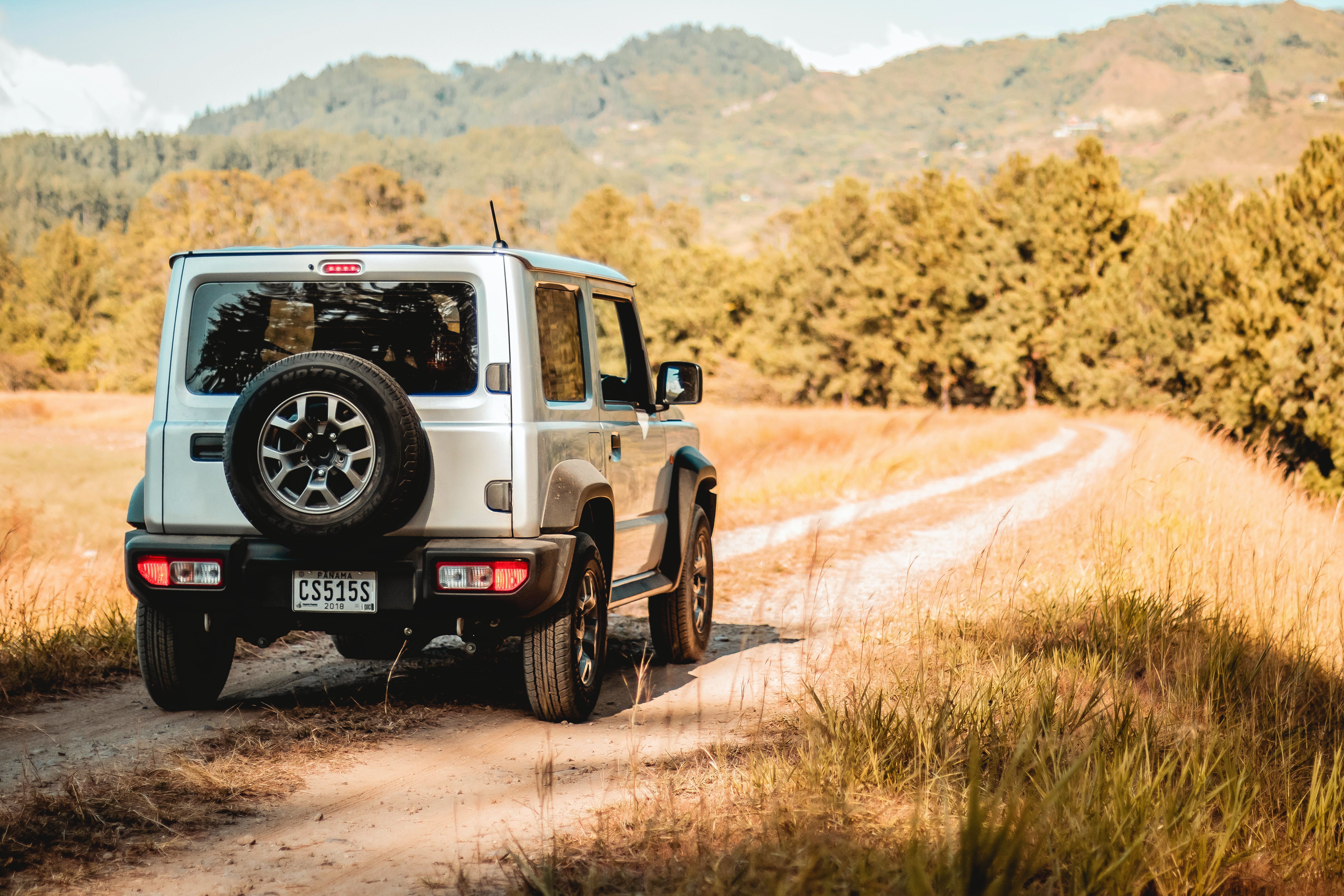 A jeep driving along a sunny country road.