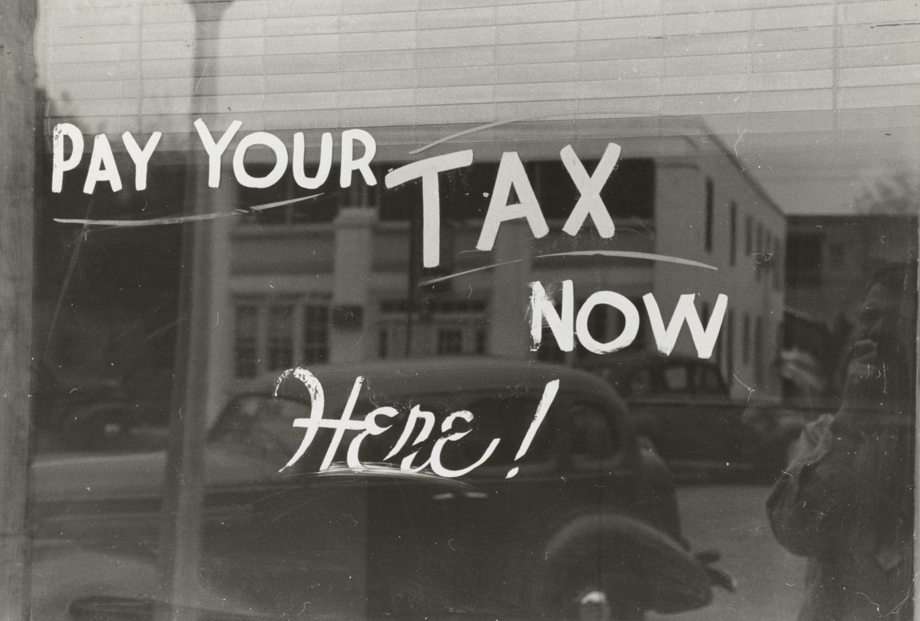 A shop window saying to pay your tax.